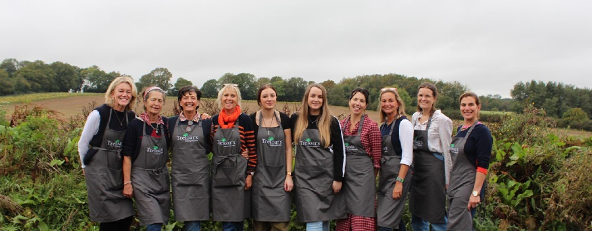 The Dummer Fair Committee with Treloar's Events Team in a group shot all wearing Treloar's aprons with the fields in the background.