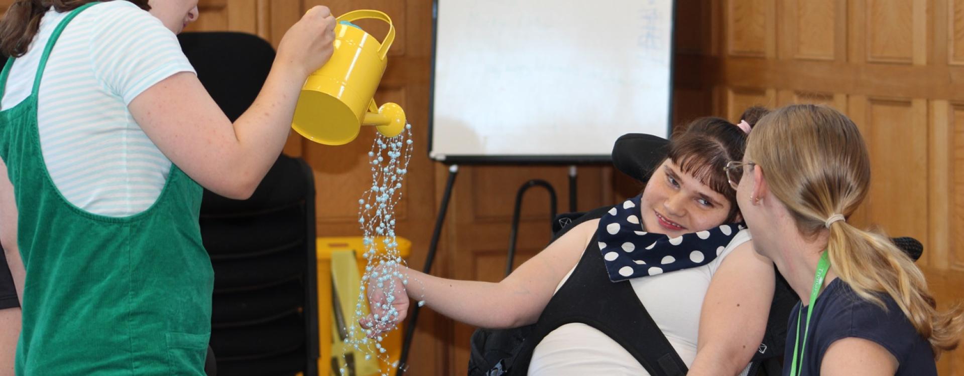 Treloar College student participating in an interactive and sensory activity: she is touch beading and her assistant is sitting next to her and looking at her face.