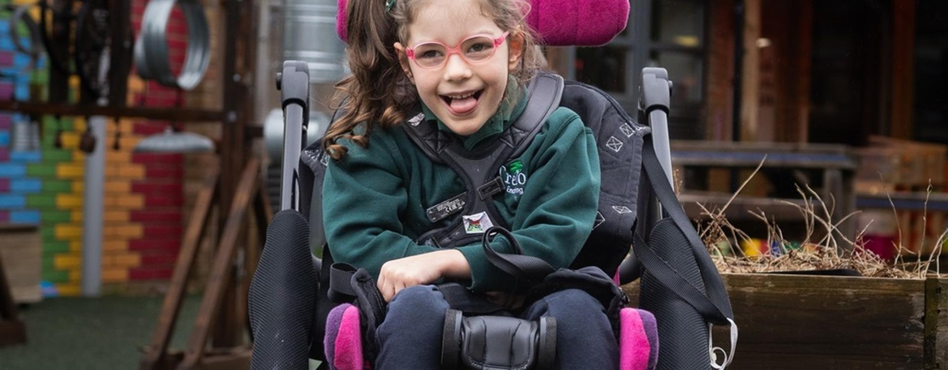 Treloar School student looking at the camera and smiling; she is wearing her pink glasses and Treloar's uniform.