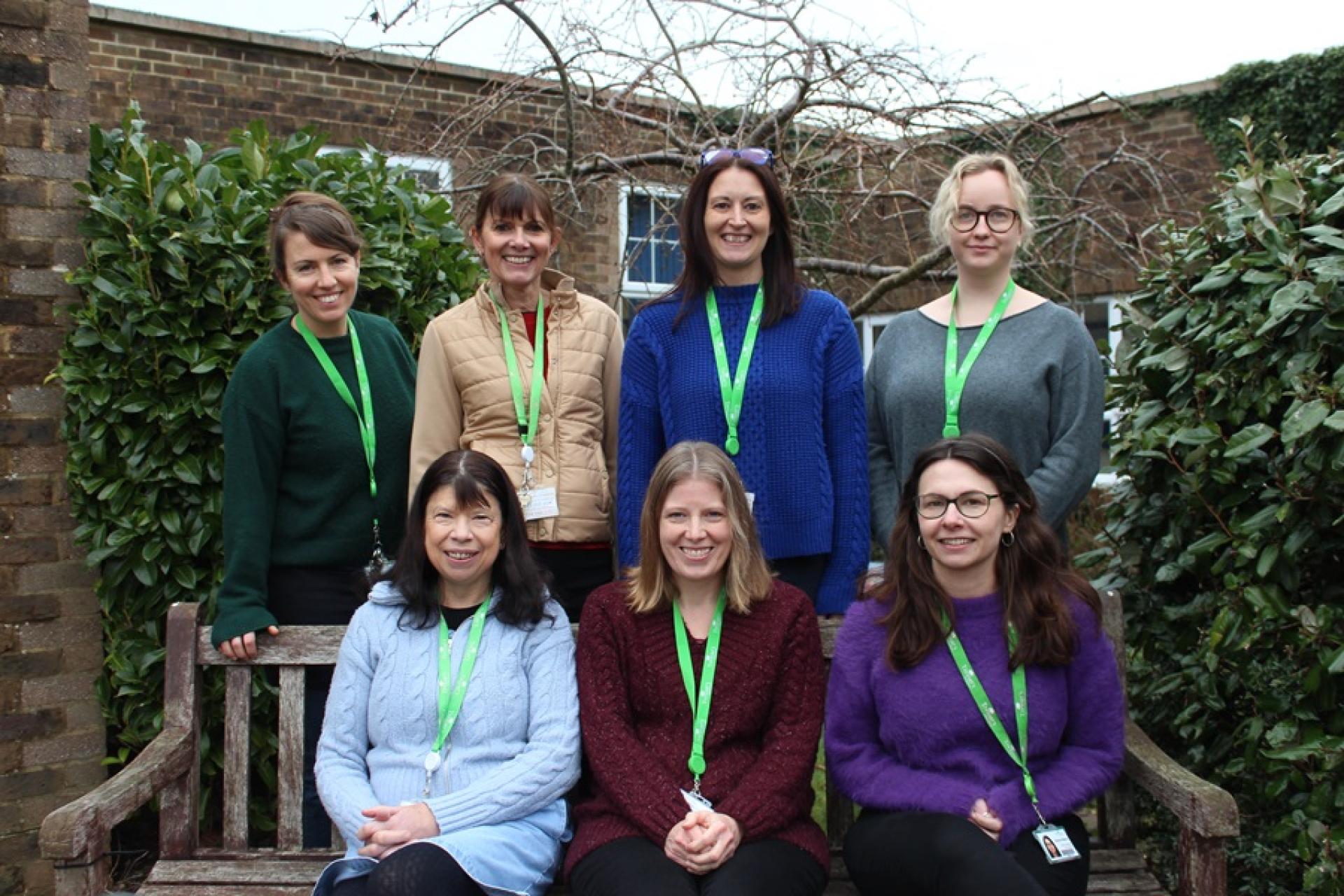 Group photo of Treloar’s Counselling Team done outdoors: 3 members of the team are sitting on a bench and 4 members are standing right behind the bench. 