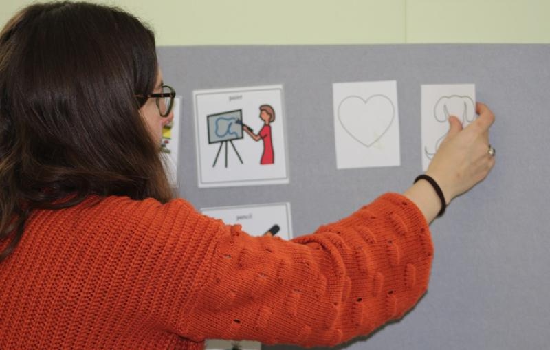 Rachel Mason, a Highly Specialist Art Therapist at Treloar's, putting up cards with images on the board.