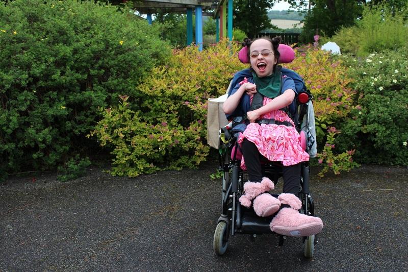 Treloar College student at her prom wearing a bright pink dress; she is smiling.