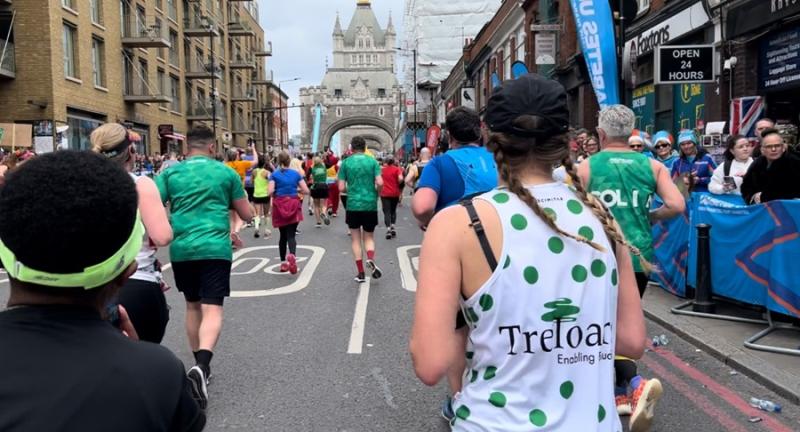 Treloar's supporter running London Marathon and wearing a branded running top with Treloar's logo at the back and green dots all over.