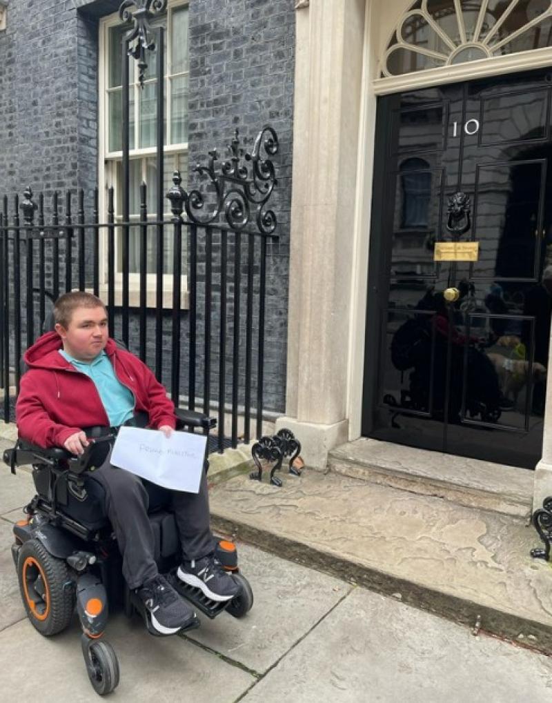 Treloar College student Ben outside Number 10 Downing Street, holding the petition.