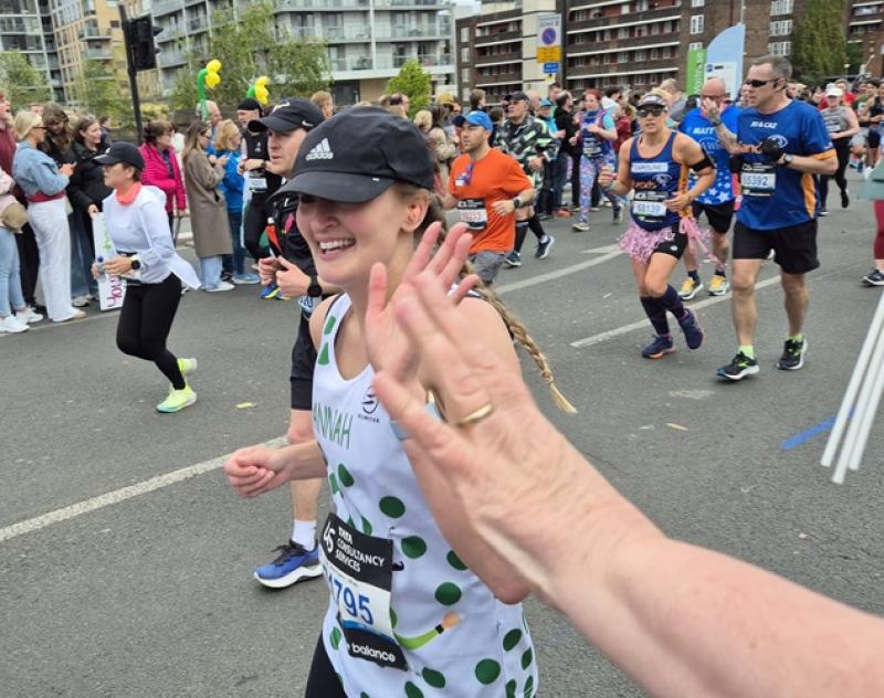 Hannah running the marathon and giving a high five to a person from the crowd.