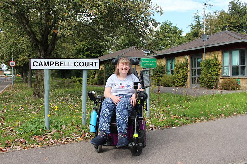 Campbell Court resident posing out the court, but the sign 'Campbell Court'.