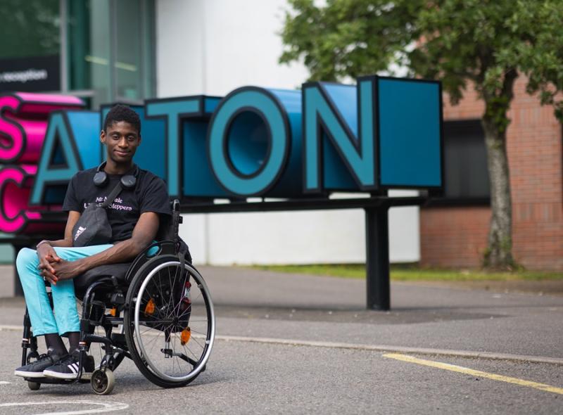 Reuben, former Treloar College student, posing for a photo in front of his college building in Alton.