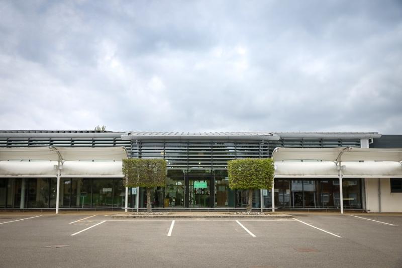 The front of Treloar's main building - empty parking spots in front of it and a cloudy sky above the building.