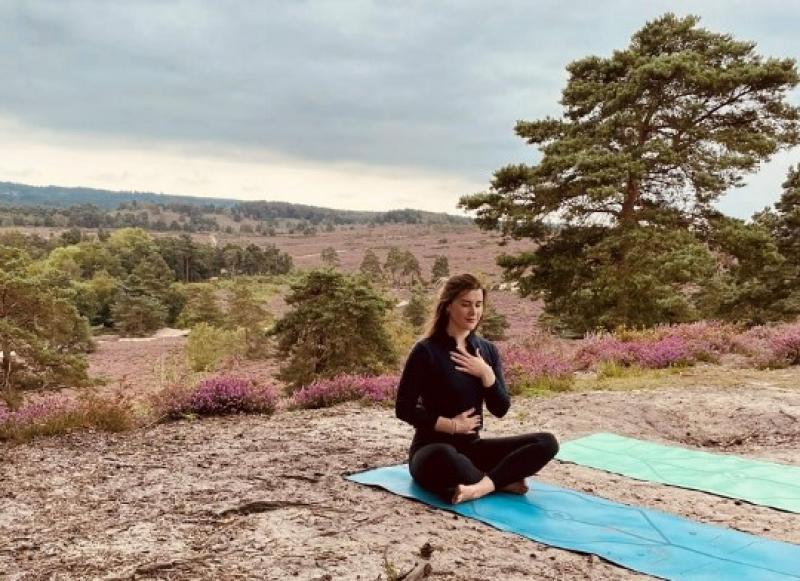 Well-being champion Sophie sitting on a matt while doing a breathing yoga exercise.