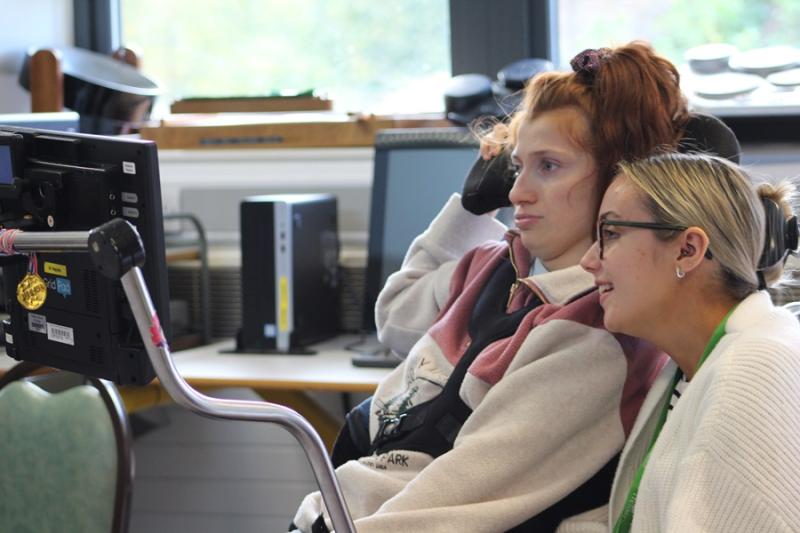 Treloar College student looking at her iPad in front of her; her assistant is sitting next to her and is also looking at the screen. They are both focused.