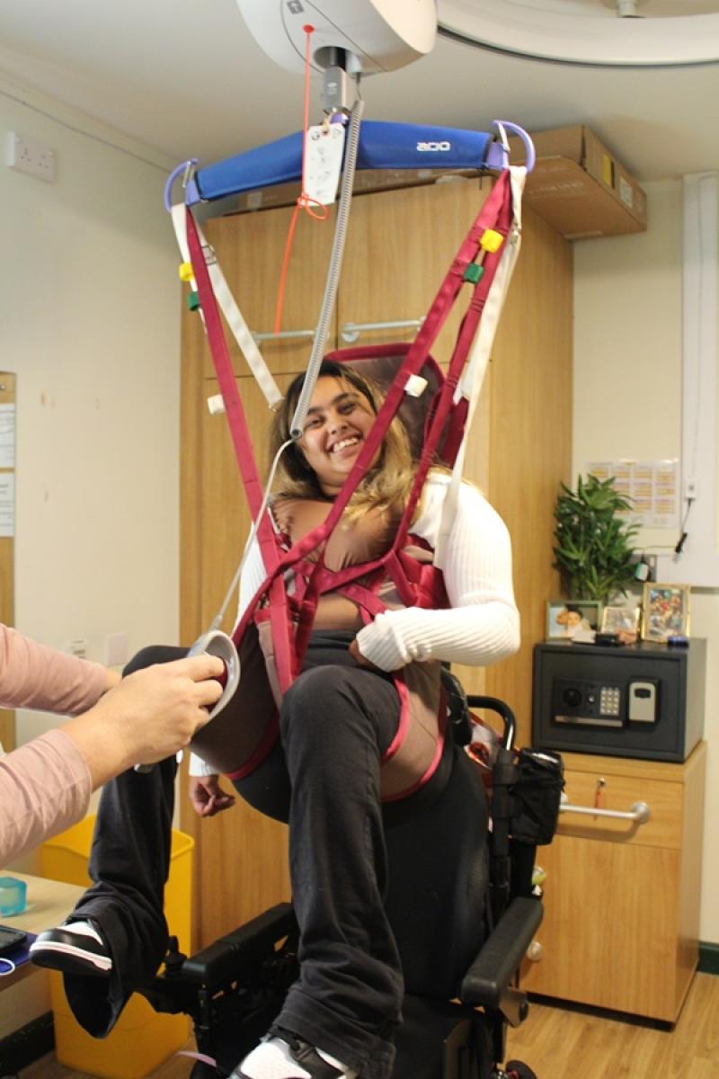 College student Amirah using a hoist in her room with her support assistant