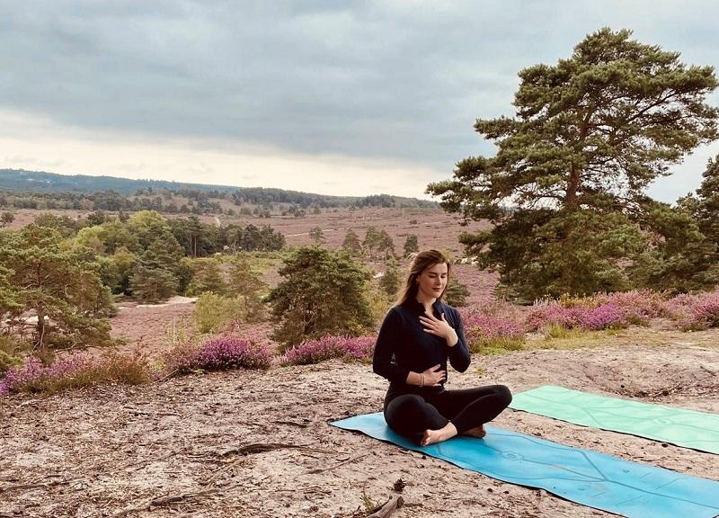 Well-being champion Sophie sitting on a matt while doing a breathing yoga exercise