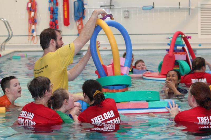 Treloar's staff and students in the pool together with students and staff from the Angermering School: they are using floating toys to build a tower.