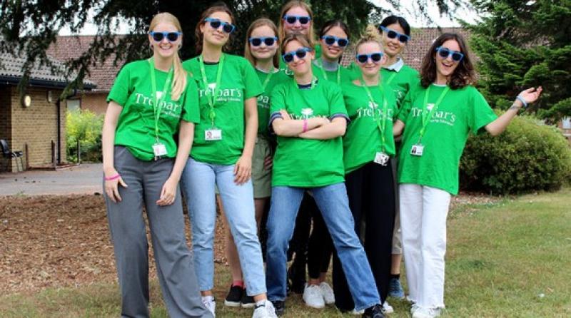 A group photo of volunteers who are all wearing bright green T-shirts with Treloar's logo on the front. They are also wearing blue sunglasses. The group is outdoors.