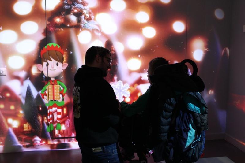 An interactive projections on the wall of a Christmas elf, accompanied by scents and sounds: Treloar College student is looking at the projection with her assistant.