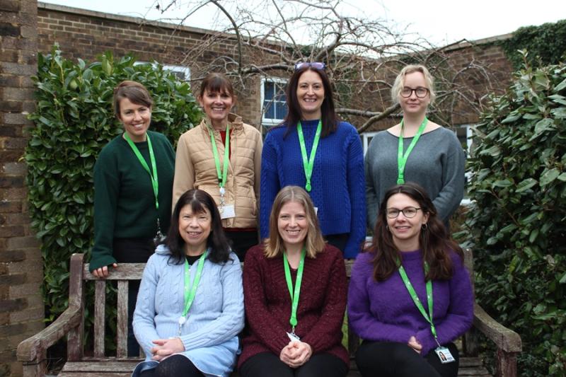 Group photo of Treloar’s Counselling Team done outdoors: 3 members of the team are sitting on a bench and 4 members are standing right behind the bench. 