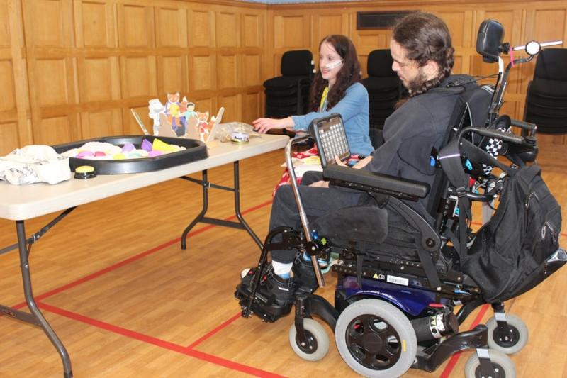 Lottie Barr from Buttons and Bubbles during her sensory workshop: she is showing different objects on a table to Treloar's student.