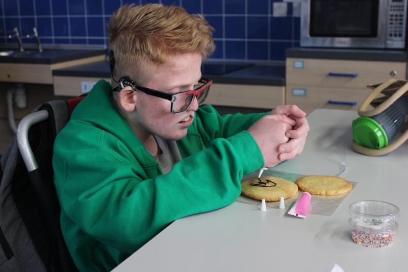 Treloar's student decorating a cookie in a school kitchen.