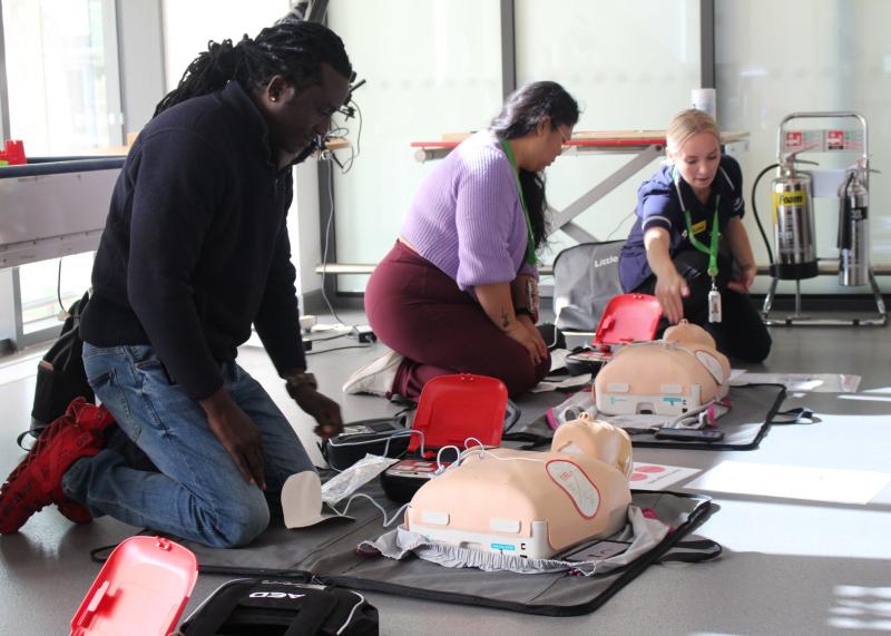 Two Treloar's staff taking part in basic life saving training, directed by a nurse