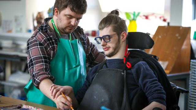 Young adult painting with a staff assistant