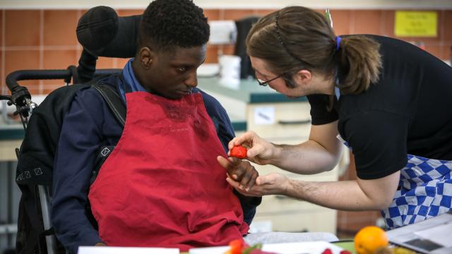 Young person working with staff in the school training kitchen