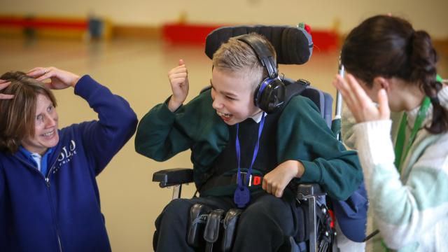 Two staff with student using gestures to communicate