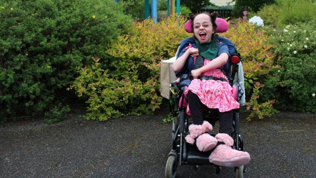 Treloar College student at her prom wearing a bright pink dress; she is smiling.