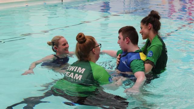 Suzanna Hext in the pool saying hello to Treloar's student who is being supported by to assistants.