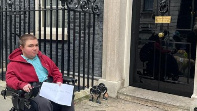 Treloar College student Ben outside Number 10 Downing Street, holding the petition.