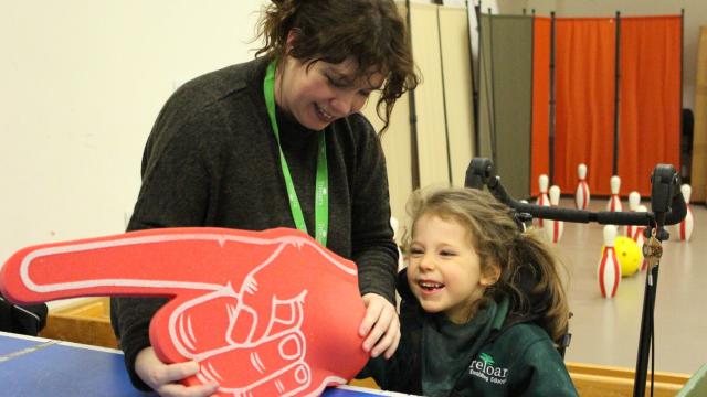 Treloar school student playing table cricket using an oversized foam hand