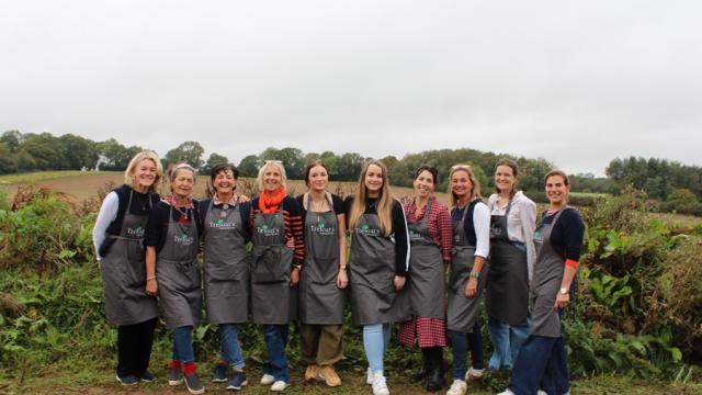 The Dummer Fair Committee with Treloar's Events Team in a group shot all wearing Treloar's aprons with the fields in the background.