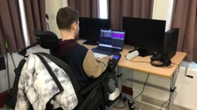 Joe at the desk working on his music using a laptop.