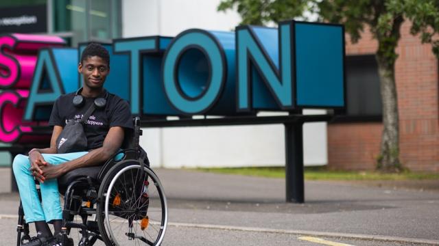 Reuben, former Treloar College student, posing for a photo in front of his college building in Alton.