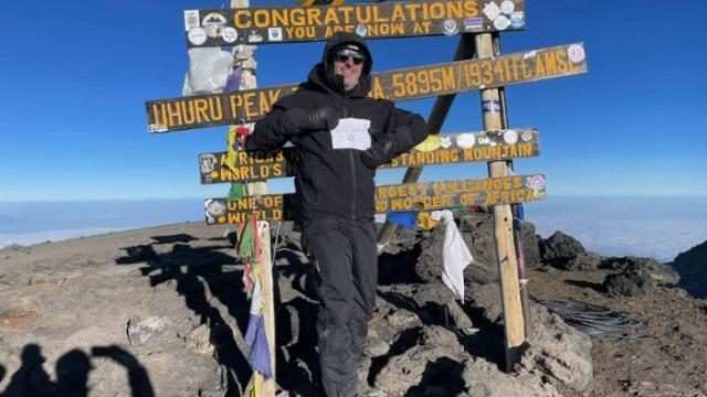 Chris reached the peak of Kilimanjaro - posing in front of a signpost.