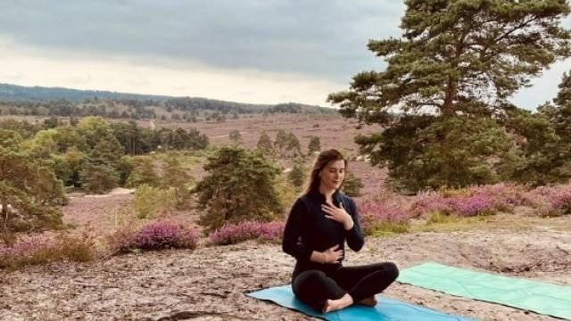 Well-being champion Sophie sitting on a matt while doing a breathing yoga exercise.