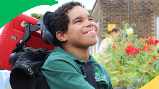 Treloar student in the piazza with red geraniums in the background and a red ipad on the back of his chair