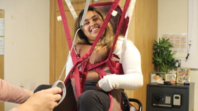 College student Amirah using a hoist in her room with her support assistant