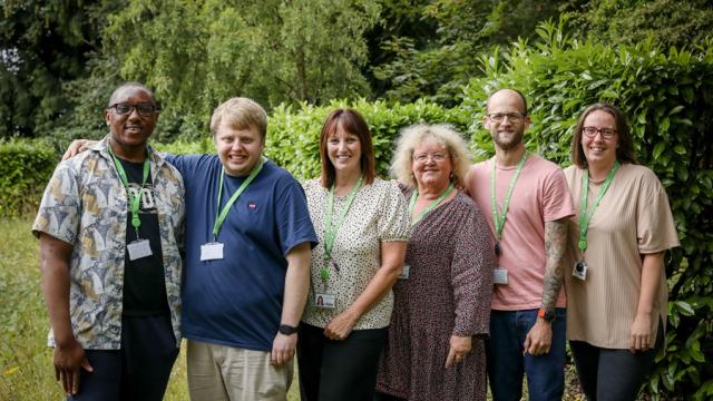 A group shot of Treloar's employees outdoors: a green lawn and shrubs in the background.