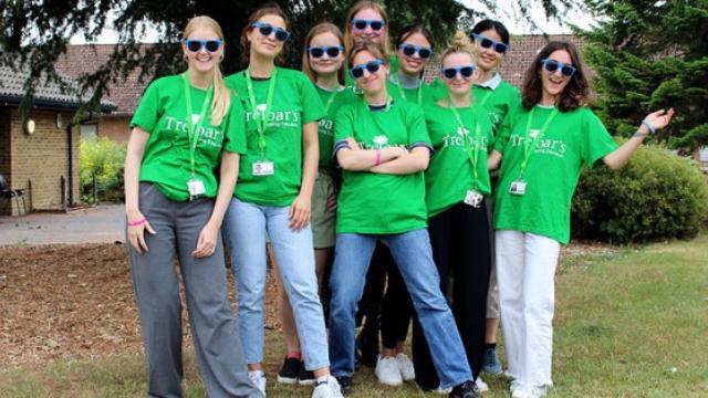 A group photo of volunteers who are all wearing bright green T-shirts with Treloar's logo on the front. They are also wearing blue sunglasses. The group is outdoors.