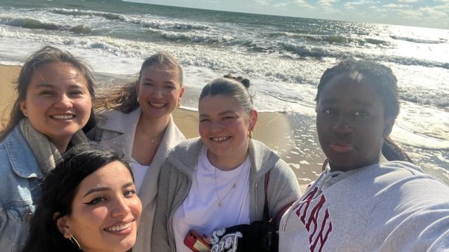 Treloar's international volunteers on the beach taking a selfie on a sunny day, sea in the background.