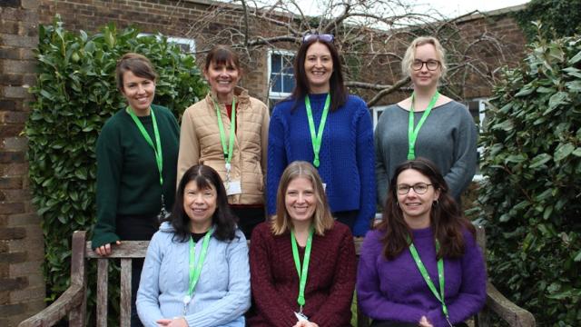 Group photo of Treloar’s Counselling Team done outdoors: 3 members of the team are sitting on a bench and 4 members are standing right behind the bench. 