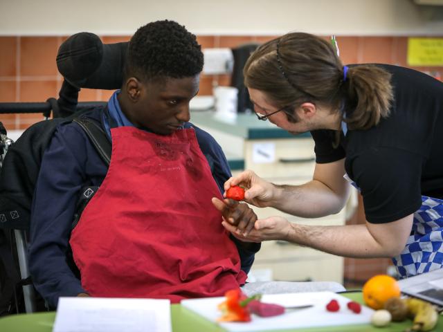 Young person working with staff in the school training kitchen