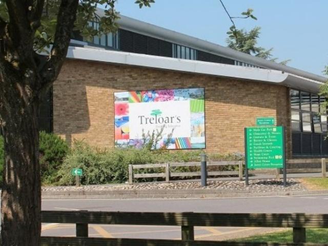 The front of Treloar's building seen from the driveway; a big logo of Treloar's attached to the wall.