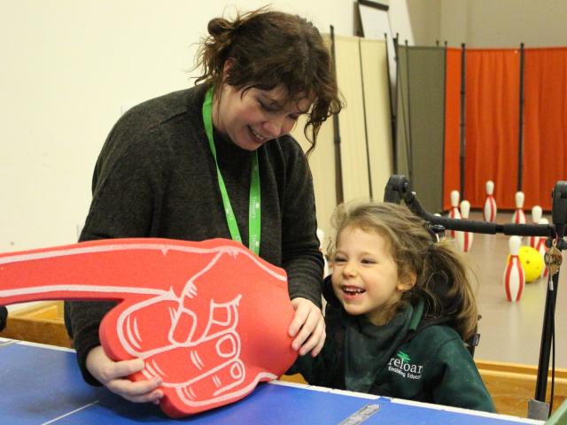 Treloar school student playing table cricket using an oversized foam hand