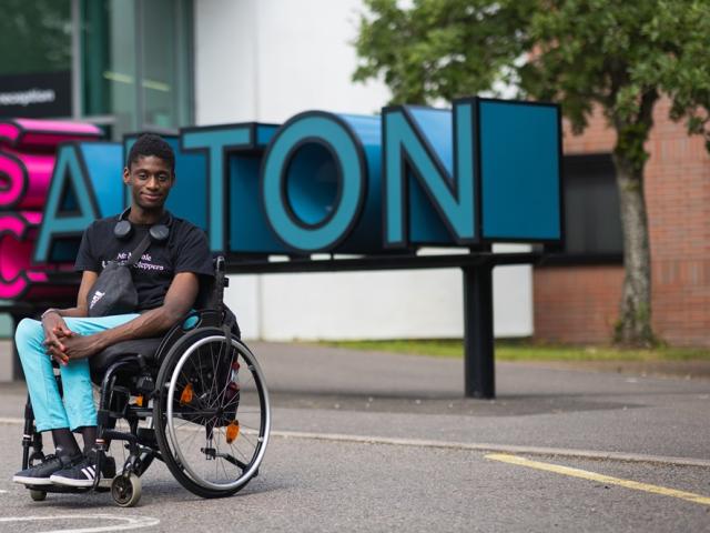 Reuben, former Treloar College student, posing for a photo in front of his college building in Alton.