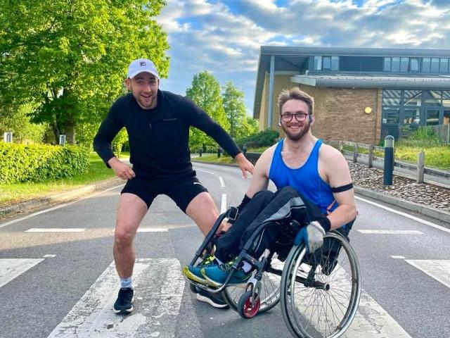 Patrick with his training with his best mate Carl outside Treloar's building - both wearing running clothes and smiling at the camera.