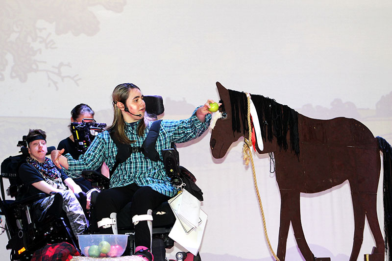 2 Treloar's students on stage during the War Horse performance; the student in the foreground is stroking a horse made out of cardboard.