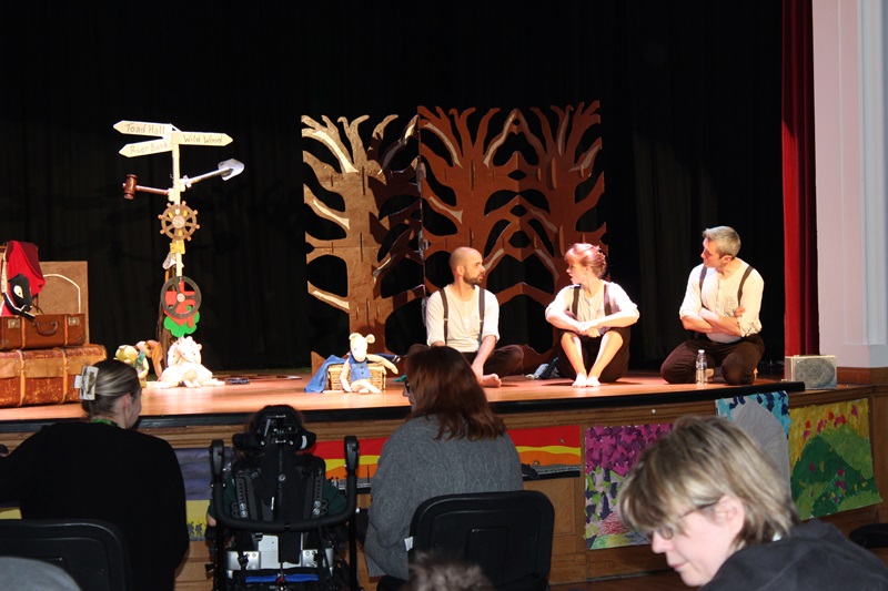 3 performers from Box Tale Soup on stage at Treloar's: all sitting on the floor - Treloar's staff and students in the audience watching